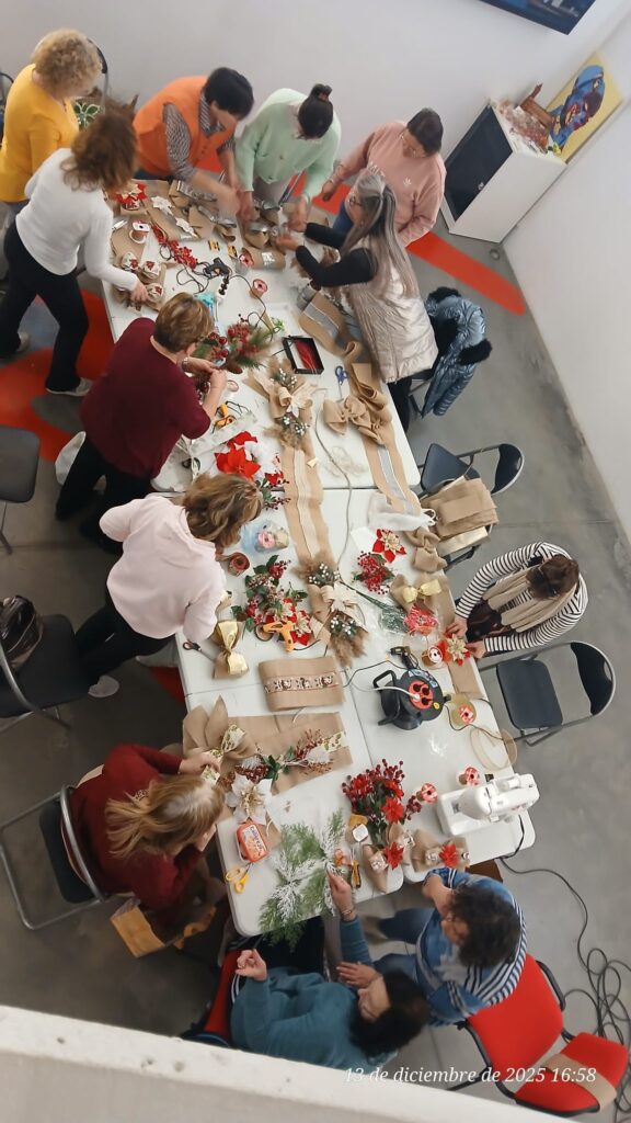 Se muestra una vista superior de una mesa rodeada de gente trabajando en manualidades navideñas.